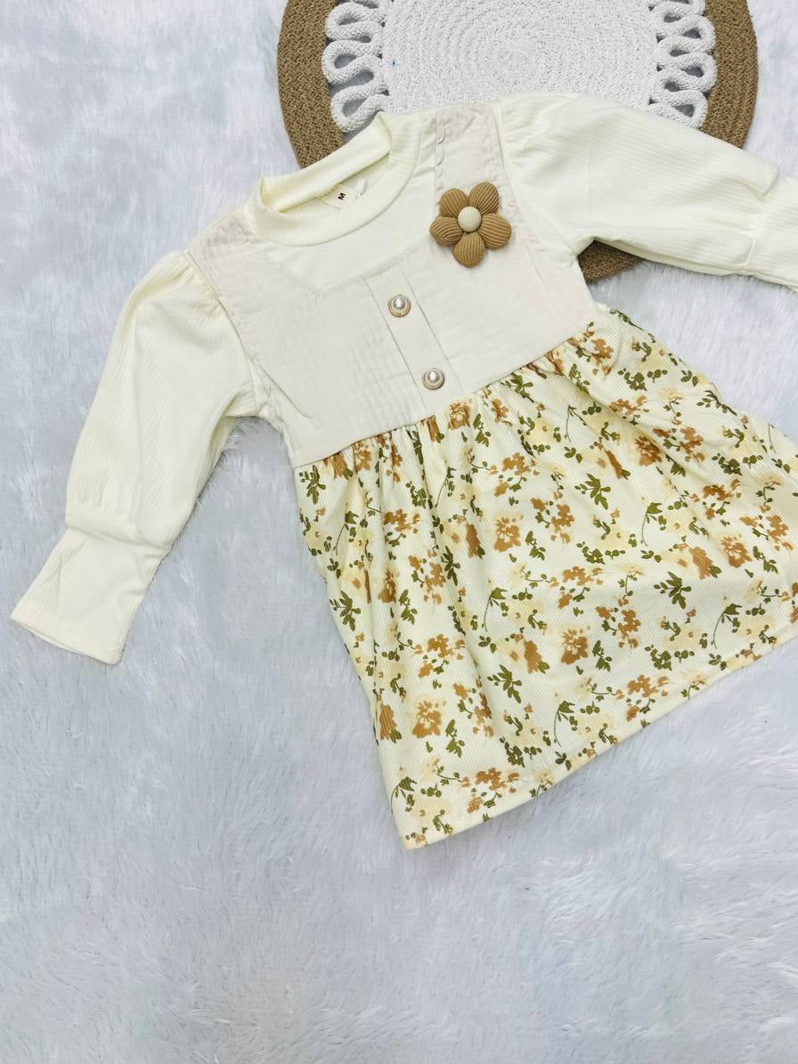 Baby dress with floral pattern and white cardigan on a textured surface