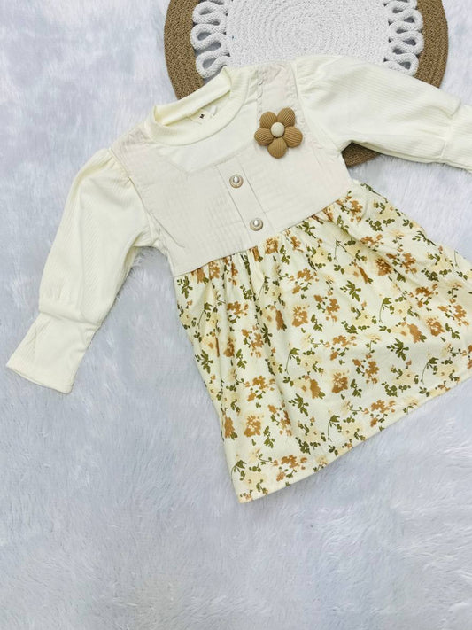 Baby dress with floral pattern and white cardigan on a textured surface